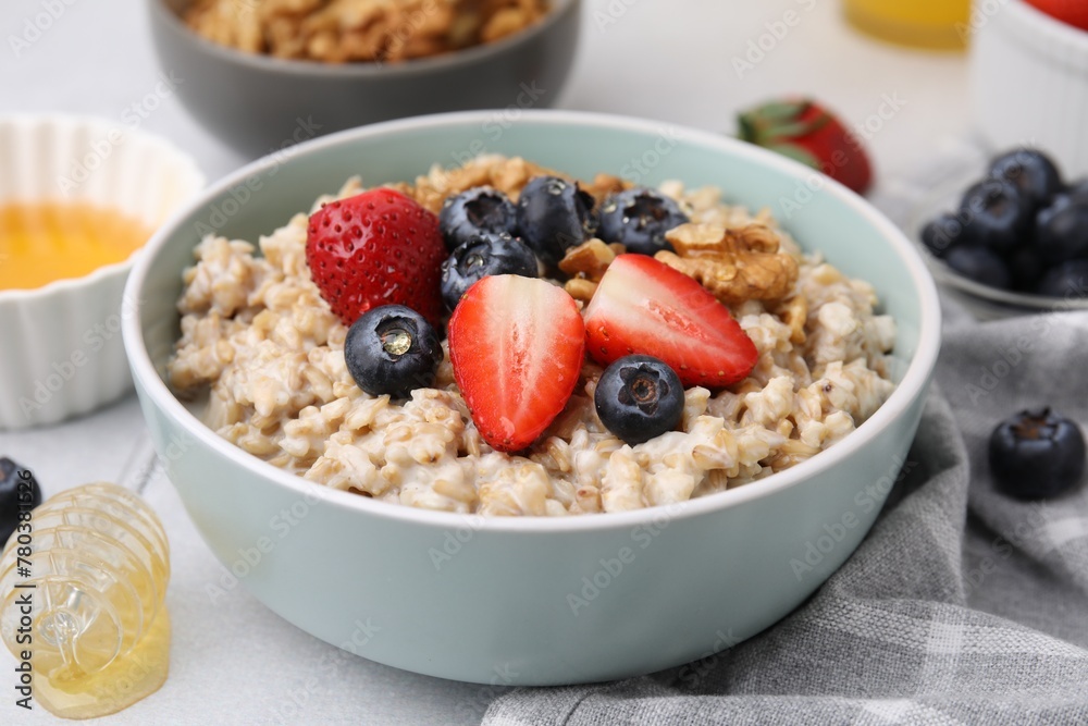 Tasty oatmeal with strawberries, blueberries and walnuts in bowl on grey table, closeup Tasty oatmeal with strawberries, blueberries and walnuts in bowl on grey table, closeup