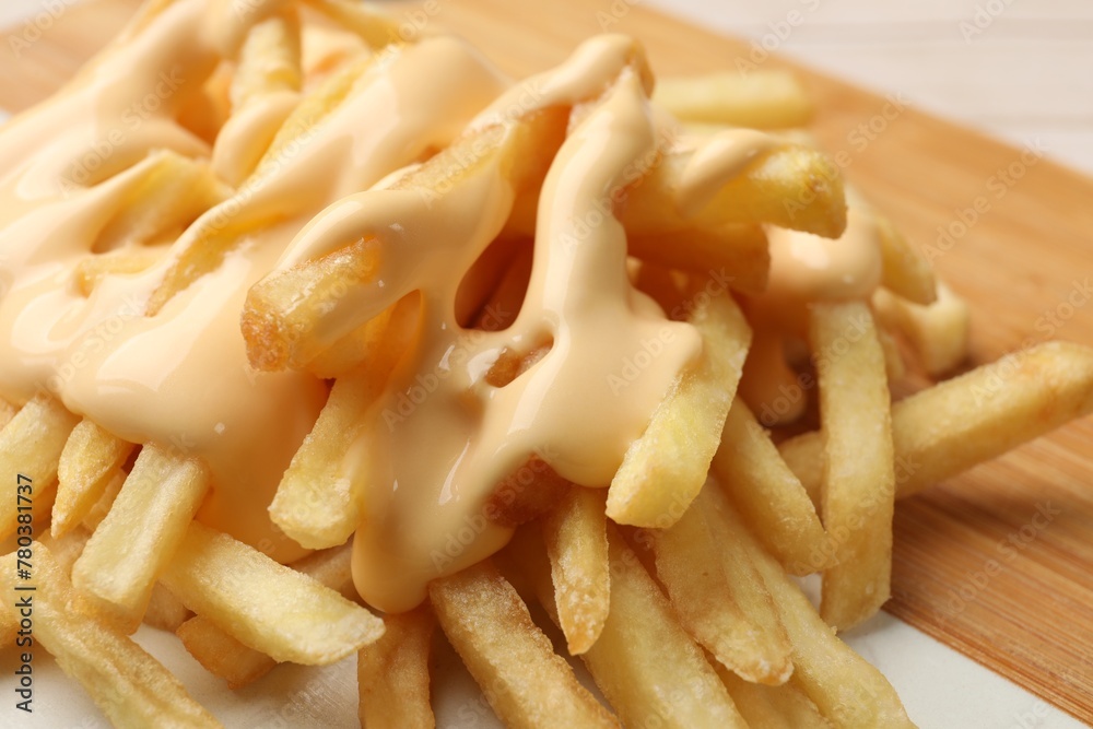 Delicious french fries with cheese sauce on board, closeup Delicious french fries with cheese sauce on board, closeup