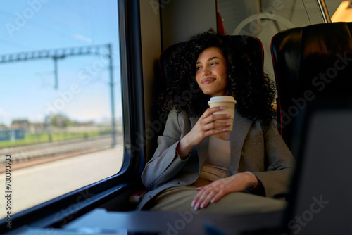 Contemplative young woman with a warm drink traveling by train.