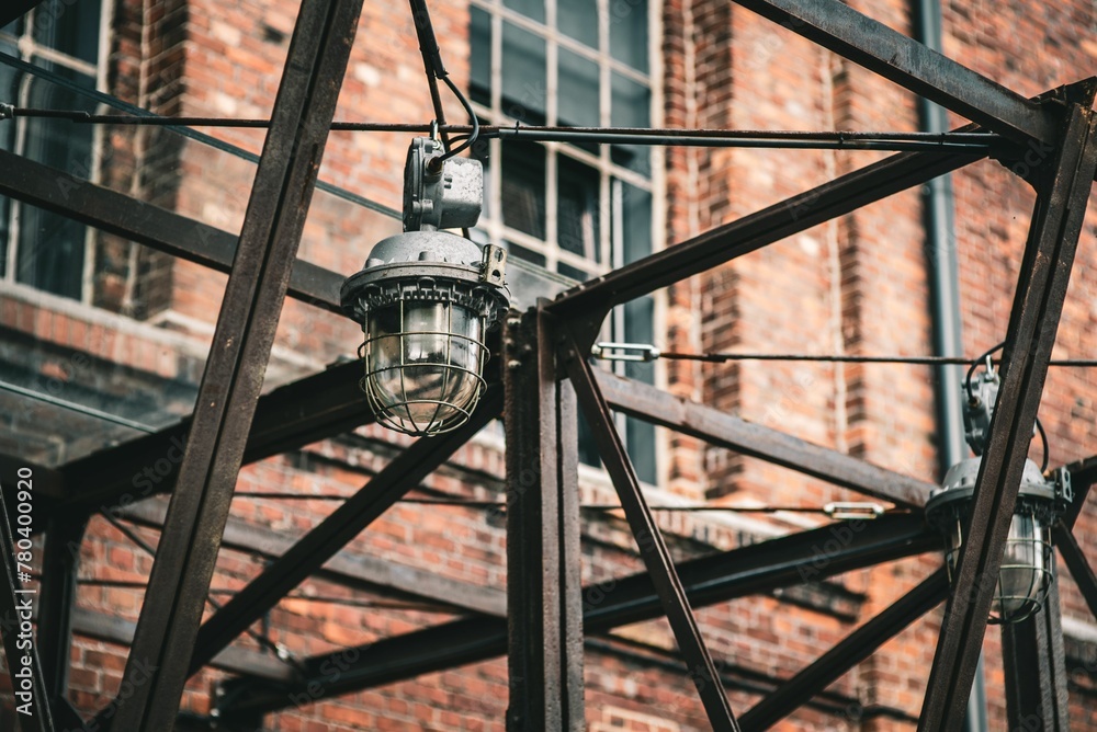 Fototapeta premium Old metal lamp hanging on the street with a blurred brick building in the background