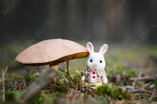 Cute white bunny statue next to a Russula mushroom in a forest
