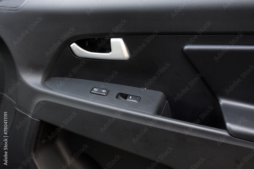 Passenger door trim. Car window controls. Door handle with power window control. Window control buttons on cars. Car interior details of door handle with windows controls and adjustments. 