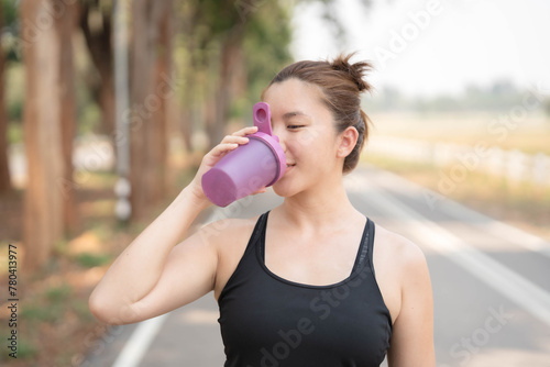 Asian woman drinking water after exercising. Taking care of your figure and staying healthy.