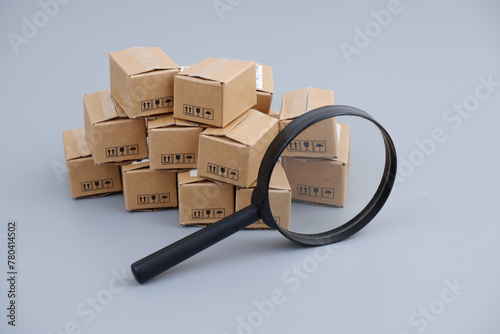 Check taxes, tariffs and shipping concept. Many carton boxes under magnifying glass.	