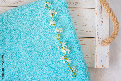 cherry blossom branch and turquoise towel on a white wooden background. spa and freshness atmosphere