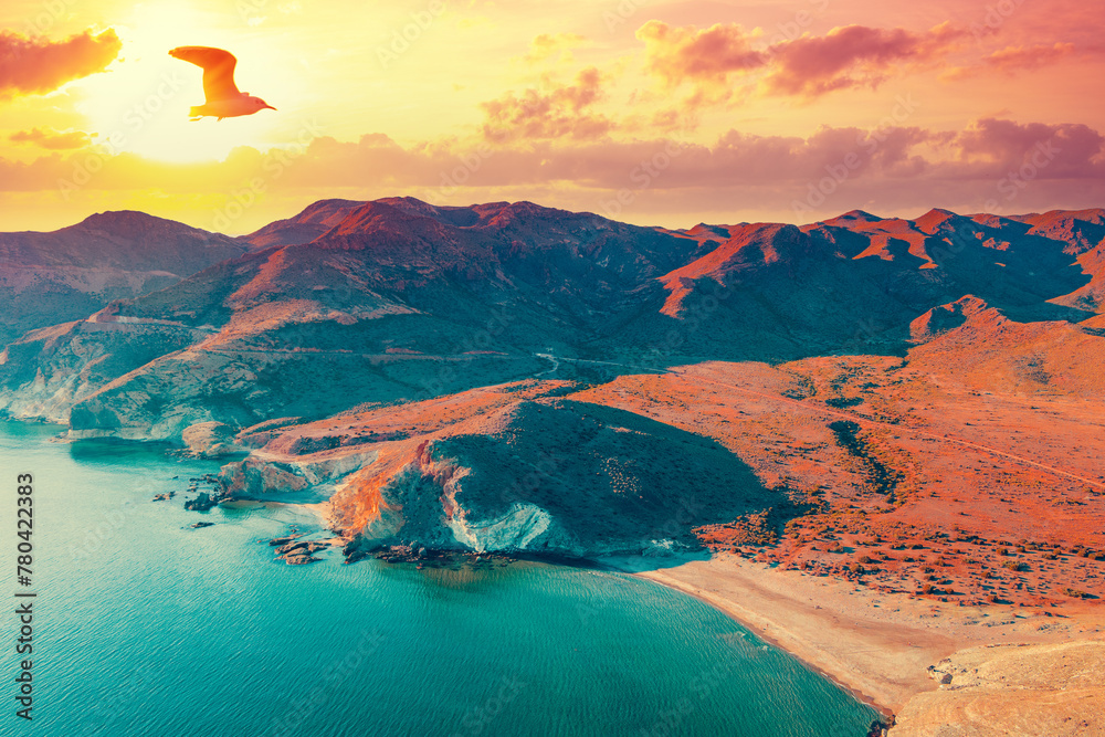 Aerial view of Rocky seashore with dramatic sunset sky. Seascape in the evening. Cabo de Gata-Níjar reserve. Almeria, Andalusia, Spain - obrazy, fototapety, plakaty 