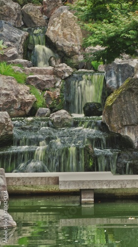 Vertical long exposure shot of a beautiful waterfall in Japanese garden