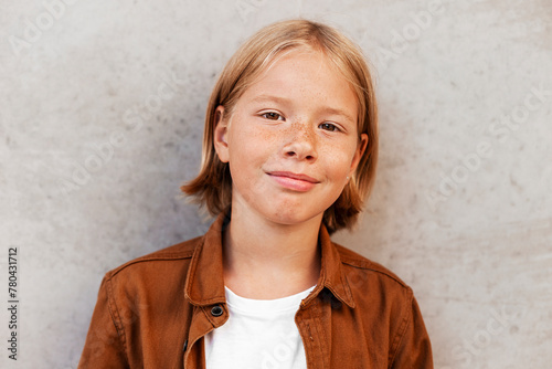 Portrait of smiling blond boy with freckles on face against gray wall photo