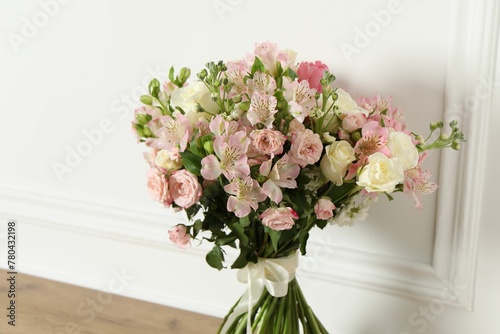 Beautiful bouquet of fresh flowers on wooden table near white wall