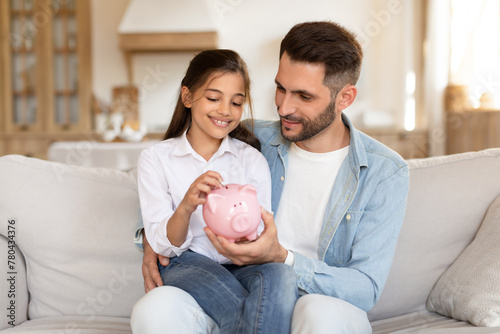 Father and daughter saving money together at home