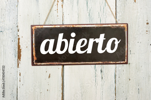 Vintage tin sign on a wooden background - Open in spanish