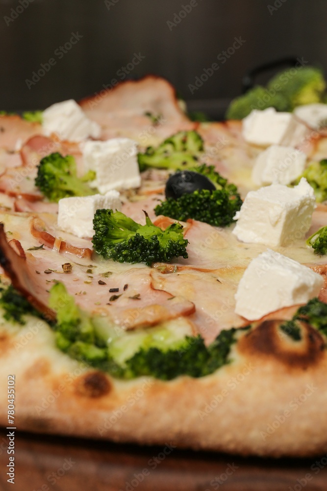 Vertical closeup shot of details on a gourmet pizza with broccoli and cheese toppings Vertical closeup shot of details on a gourmet pizza with broccoli and cheese toppings