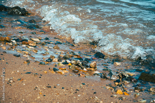 Closeup of small stones on a sandy beach with waves