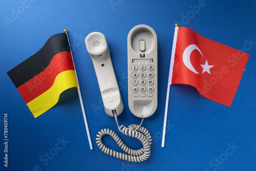 Flag of Germany, Turkey and old corded telephone on a blue background, concept on the theme of telephone conversations between countries