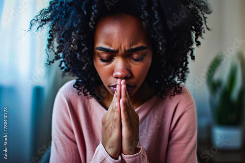 A visibly upset woman with hands clasped in a prayerful gesture seeking solace or help photo