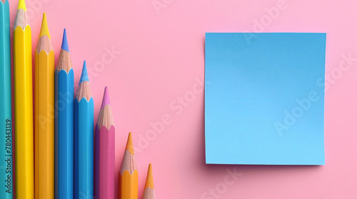 Back to school concept. A blue color post it paper, pink, blue and yellow pencils on pastel pink background. photo