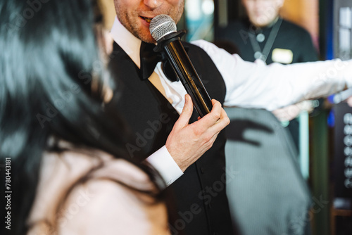 Man in formal wear gestures with microphone to musician, adding fun to the event