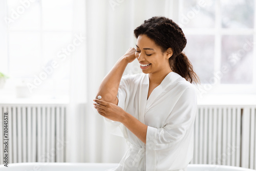 Woman applying skincare in bathroom at home photo