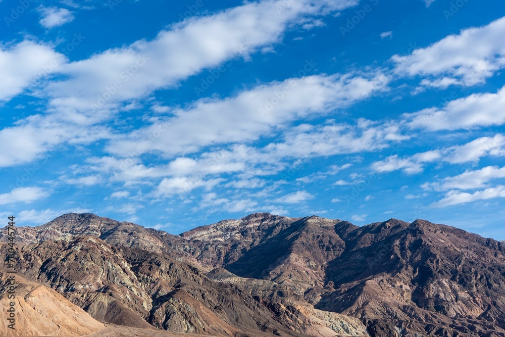 Dramatic shot of striped clouds over mountain ridge in Death Valley on a sunny day