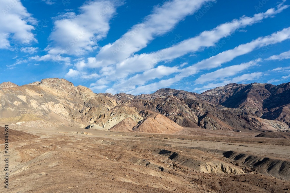 Dramatic shot of striped clouds over mountain ridge in Death Valley on a sunny day