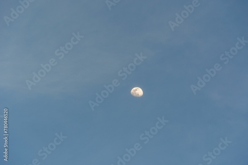 Beautiful shot of the white half-moon in a bright blue sky photo