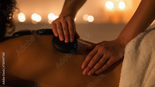 Woman getting hot stones back massage in spa salon photo