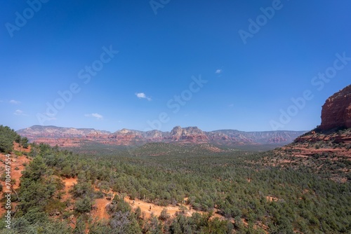 Beautiful view of a green desert and rock formations under a clear blue sky in Sedona, Arizona.