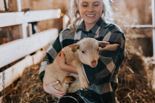 Smiling woman carrying sheep kid in farm photo