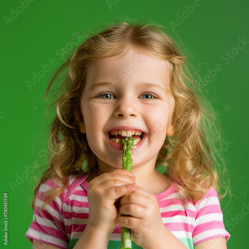 Beautiful young girl bits on green asparagus and laugh