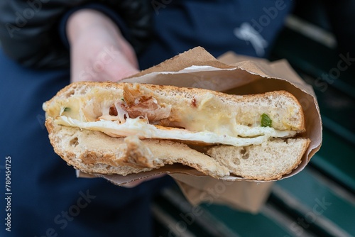 Closeup of a person holding a sandwich in a paper bag captured from top view photo