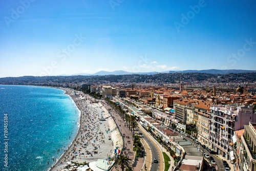 Drone shot of people on the sandy beach and the coastal buildings on a sunny day in Nice, France