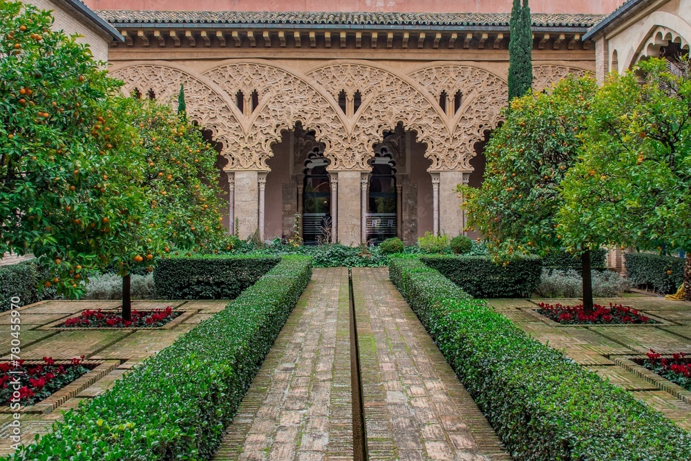 Image of an Aljaferia Palace garden with green trees and grass.