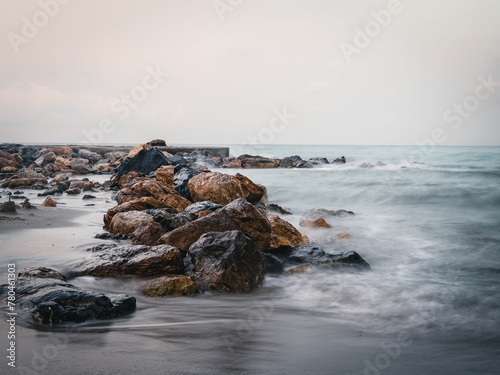 Sea waves calmly hitting a sandy beach with stones