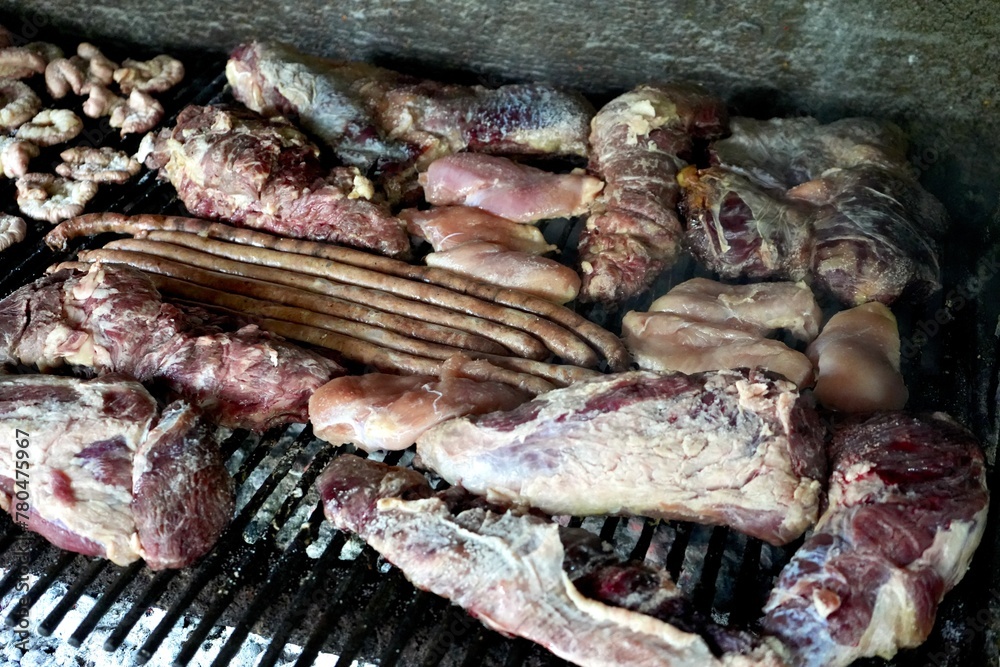 A Varierty of Meats cooking on a charcoal heated bbq.