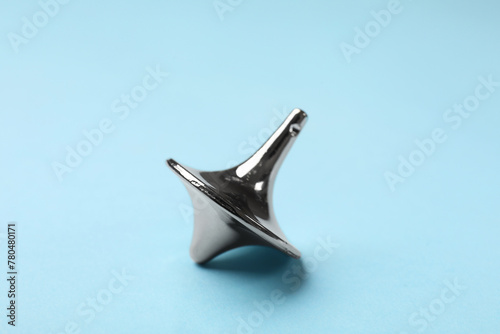 One silver spinning top on light blue background, closeup