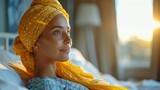Giovane donna con turbante in letto di ospedale per la cura del cancro, sguardo sereno