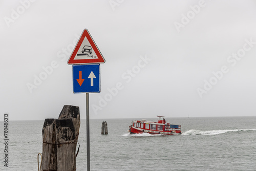 Obraz na płótnie Traffic sign priority in oncoming traffic and attention roadside on the coast of the Venice Lagoon. Passenger ferry in the background w salonie
