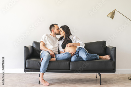 Pregnant couple sitting on couch in living room