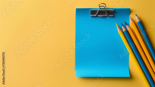 Back to school concept. A blue color post it paper and pencils on yellow background with copyspace. photo