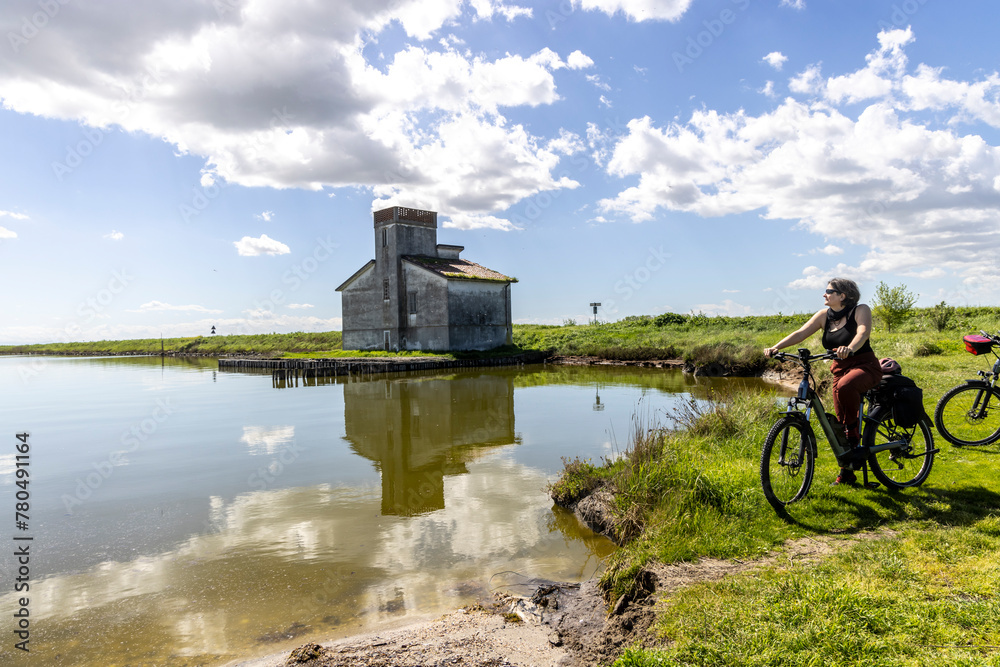 Woman cycles on an e-bike through the Po Delta in Northern Italy