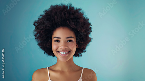 Beautiful african american girl with an afro hairstyle smiling on pastel blue background 