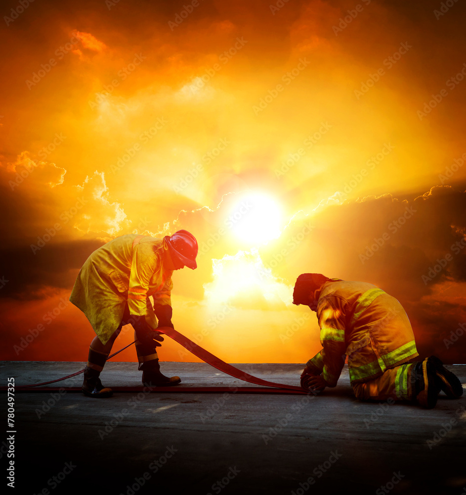 Firefighters are preparing their fire hoses to combat the blaze - obrazy, fototapety, plakaty 