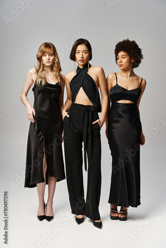 Three beautiful women, representing diversity, standing elegantly against a grey studio background.
