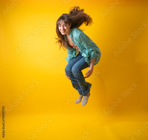 Energetic Young Woman Jumping with Joy on Yellow Background