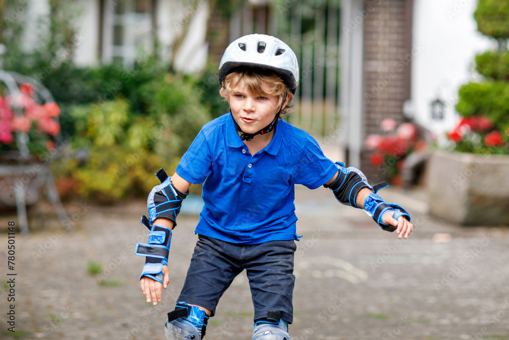 Portrait of little school kid boy in safety protection clothes scating with rollers. Active sporty child doing sports on summer day. Outdoor activity for kids. Portrait of little school kid boy in safety protection clothes scating with rollers. Active sporty child doing sports on summer day. Outdoor activity for kids.