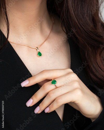 woman with emerald necklace and woman's hand with an emerald ring