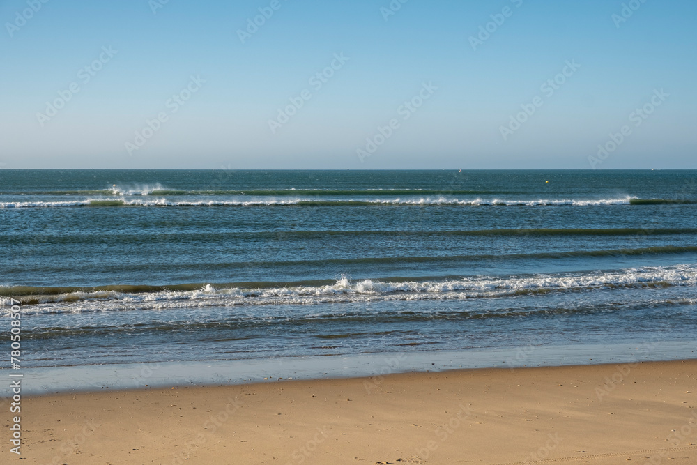 Detail of the waves of the Atlantic sea beating on the golden sand beach during the summer holidays in the province of Huelva, Spain.