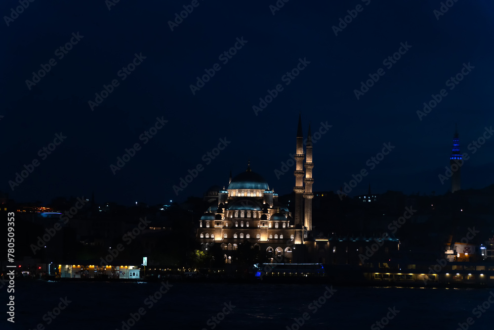 View from the ferry to the illuminated New Mosque, Yeni Kami at night, Istanbul, Turkey.
