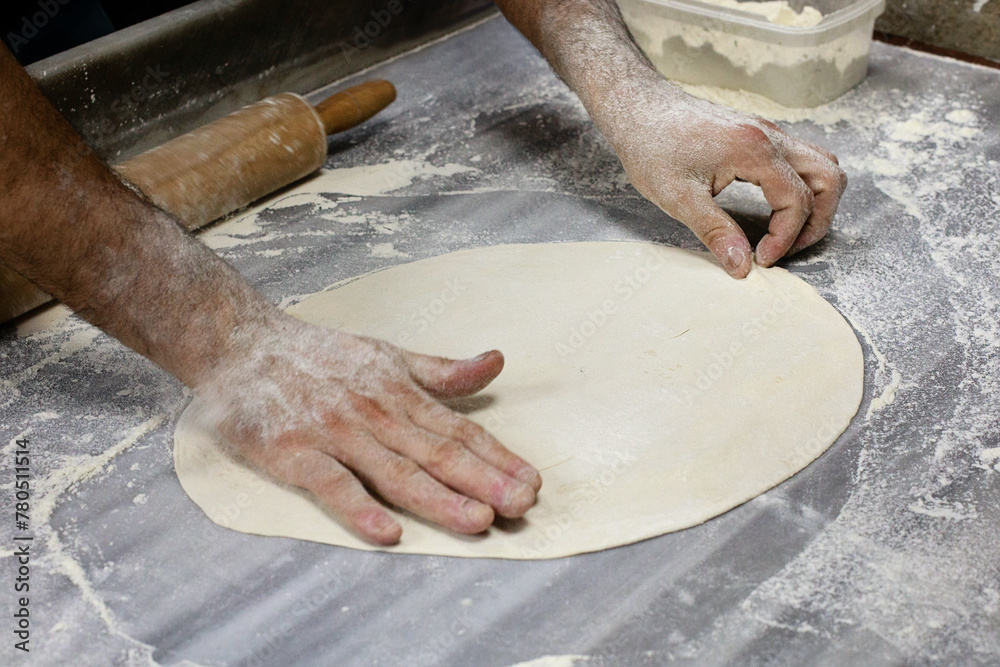 Preparation of the dough . The dough rolling the man's hands on table with flour