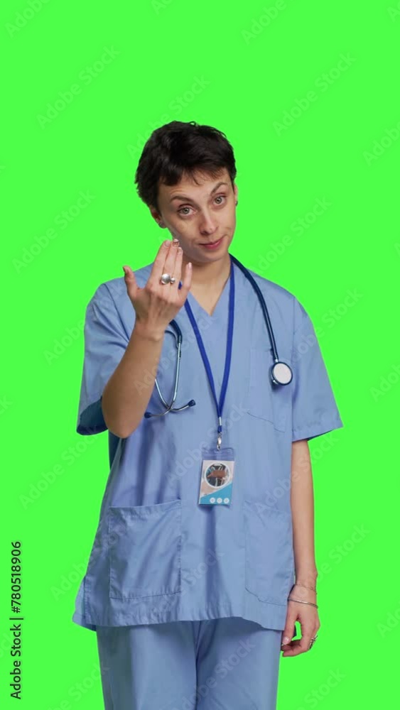 Front view Medical assistant asking a person to come over closer against greenscreen backdrop, inviting patient to approach. Nurse in scrubs calling someone at checkup examination, young surgeon Front view Medical assistant asking a person to come over closer against greenscreen backdrop, inviting patient to approach. Nurse in scrubs calling someone at checkup examination, young surgeon